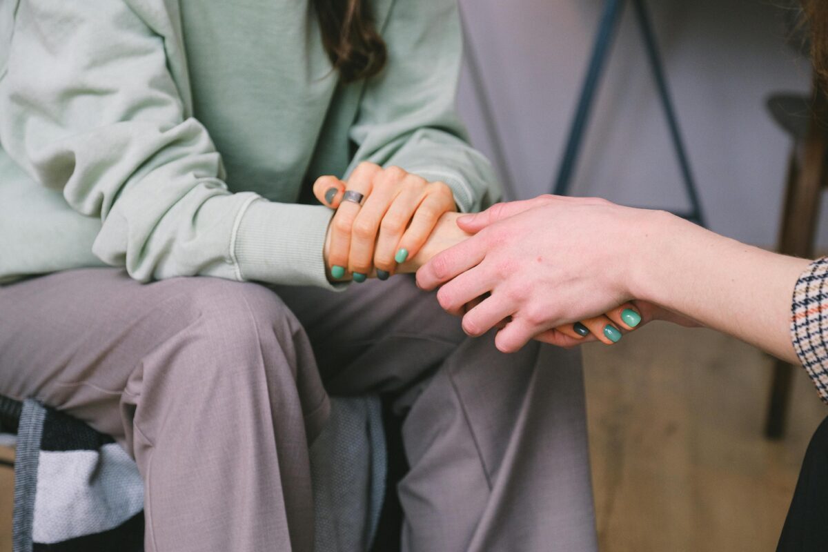 A psychologist gently holding a client’s hands during an ADHD assessment, offering comfort and support.